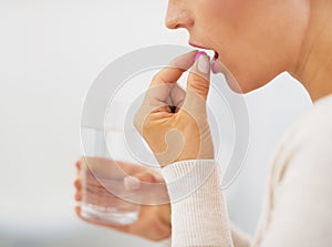 Closeup on young woman eating pill