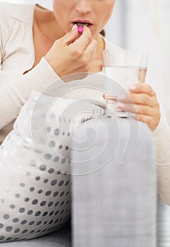 Closeup on young woman eating pill