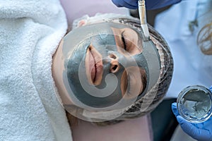 Closeup of young woman getting hydrating procedure facial spa massage by dermatologist in clinic