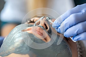 Closeup of young woman getting hydrating procedure facial spa massage by dermatologist in clinic
