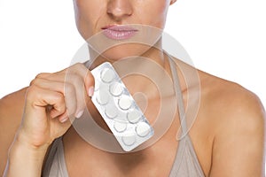 Closeup on young woman holding blistering package of pills