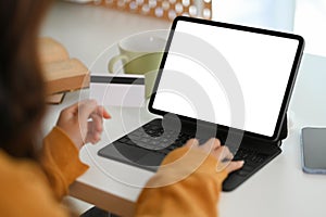 Closeup young woman holding credit card and using digital tablet making purchase on webstores