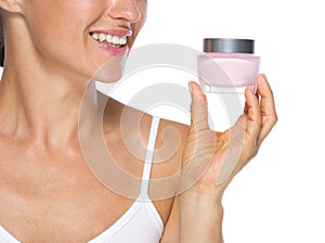 Closeup on young woman looking on cream bottle