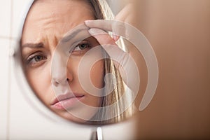 Closeup of young woman looking into mirror.