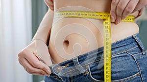 CLoseup of young woman measuring her waist after loosing weight. Concept of dieting, loosing weight and healthy