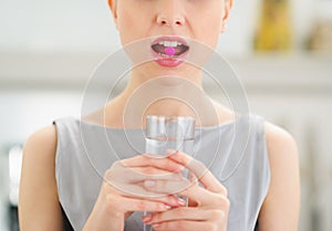 Closeup on young woman with pill in mouth