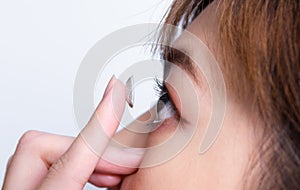 Closeup young woman putting contact lens in her eye