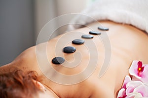 Closeup on young woman receiving hot stone massage