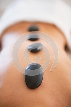 Closeup on young woman receiving hot stone massage