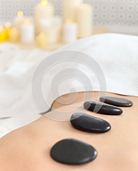 Closeup of young woman receiving hot stone massage