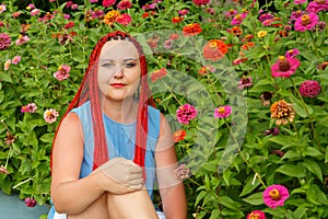 Closeup of a young woman with red hair among red orange flowers. photo