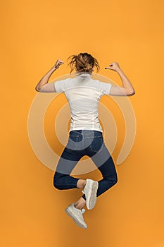 Closeup of young woman`s body in empty white t-shirt on orange background. Mock up for disign concept