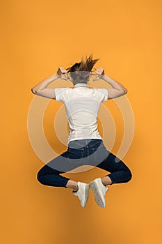 Closeup of young woman`s body in empty white t-shirt on orange background. Mock up for disign concept