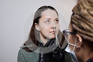 Closeup of a young woman's visage with piercing septum hanging from her nose.