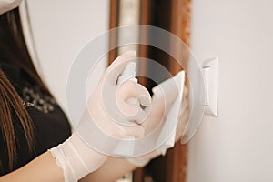 Closeup of young woman wiping doorknob on touching surfaces with antibacterial disinfecting wipe. Female killing corona