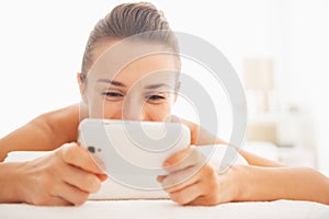 Closeup on young woman writing sms while laying on massage table