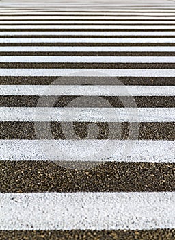 Closeup zebra pedestrian crossing on the asphalt road. White stripes on black road