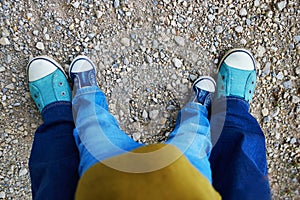 Closeupe of legs of an adult and a toddler in jeans and sneakers