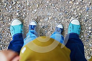 Closeupe of legs of an adult and a toddler in jeans and sneakers