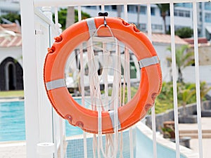 Closeyp orange lifebuoy on a white pool fence