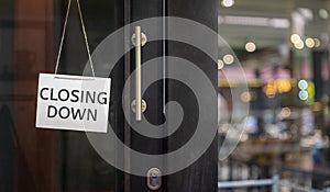 Closing Down  sign painted on the window of a dress shop