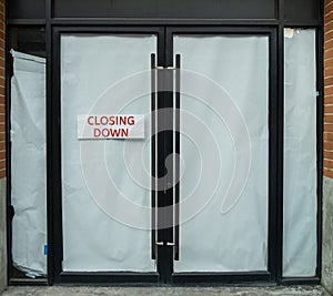Closing Down sign painted on the window of a dress shop