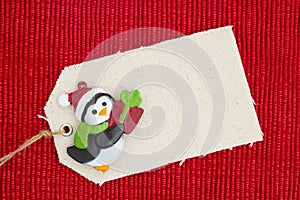 A cloth gift tag with a Christmas penguin on shiny red material photo