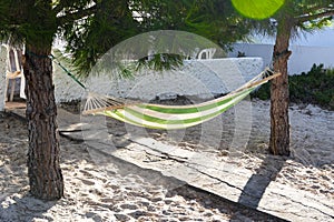 Cloth hammock hung between two pine trees at the entrance of a house on the Portuguese coast