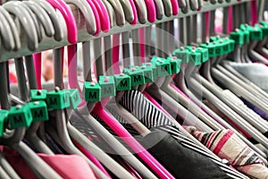 Cloth hangers with various women clothing in thrift shop, detail on M size marks