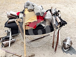 The clothes, armor and weapons of medieval knight lie mountain on felt in the open air. Protective antique helmet, chainmail,