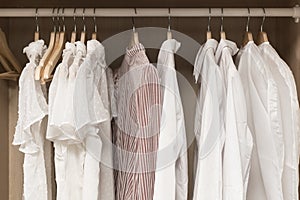 Clothes in the closet. Women's light vintage clothes on hangers in the closet of the dressing room. Fashion trends