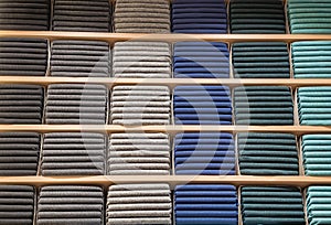 Clothes displayed in store. Copy spase for text. Lot warm sweaters of different color are neatly stacked in a row on the
