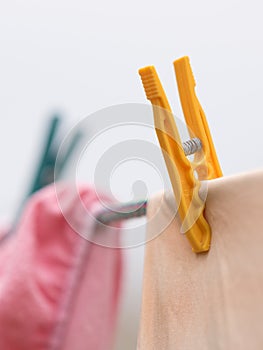 Clothes are dried with plastic clothespins in white background