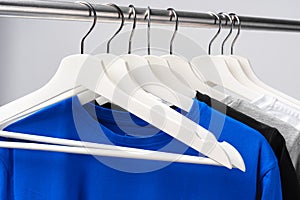 Clothes hang on clothing rack over white background.