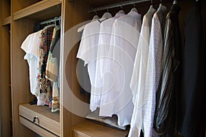 Clothes hang on a shelf in a designer clothes store, modern closet with row of cloths hanging in wardrobe, vintage rooms