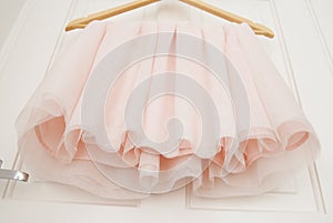 Clothes hanger with pink girl tutu dress isolated on the white door. Fashion, baby clothes.