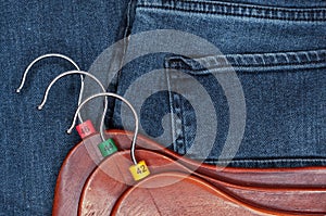 Clothes hangers with multicolored plastic size labels on a denim backdrop