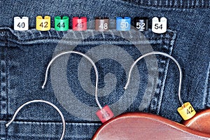 Clothes hangers with multicolored plastic size labels on a denim backdrop