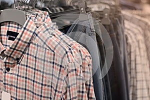 Clothes on hangers in store. Mens shirts hang on clothing rack. Shopping time concept