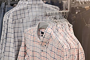 Clothes on hangers in store. Mens shirts hang on clothing rack. Shopping time concept