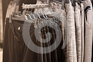 Clothes on hangers in store. Sports pants hang on clothing rack. Shopping time concept