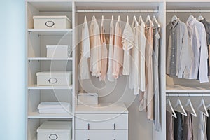 Clothes hanging on rail in white wardrobe