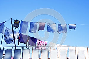 Clothes hanging to dry on a clothesline outdoors against a blue sky on a sunny day.
