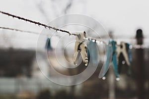 Clothes pins on wire. Rope with pins and raindrops. Laundry concept. Rainy day in village. Rural still life. Water drops and pins.