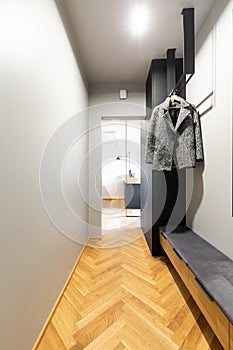 Clothes on rack above countertop in anteroom interior with wooden floor and light. Real photo