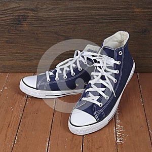 Clothes, shoes and accessories - pair blue gumshoes wooden background