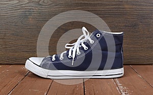 Clothes, shoes and accessories - side view one blue gumshoes wooden background