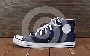 Clothes, shoes and accessories - side view one blue gumshoes wooden background