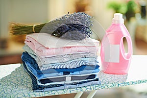 Clothes, softener and bunch of lavender on ironing board