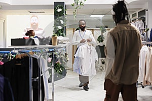 Clothes store worker carrying shirts for customer to try